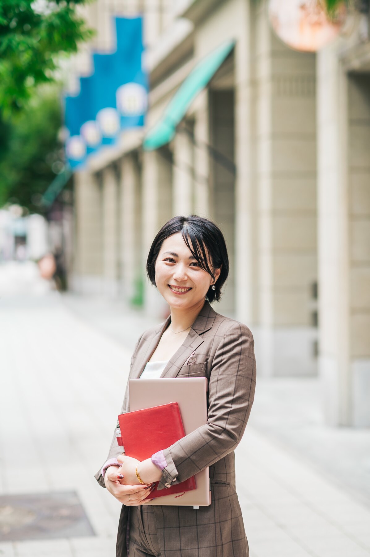 街中で書類を手に微笑む井上なるみ